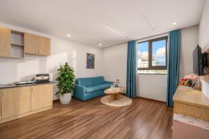 a living room with a blue couch and a kitchen at Lumina Hotel & Apartment in Danang