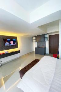 a bedroom with a white bed and a tv on the wall at Grand Kamala Lagoon by Whitebox in Bekasi