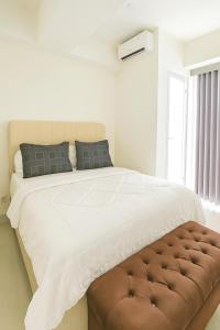 a bedroom with a large bed with a brown ottoman at Grand Kamala Lagoon by Whitebox in Bekasi +8 photos