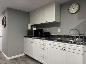 a kitchen with white cabinets and a clock on the wall at Private Apartment for Business & Couples in Sudbury +20 photos