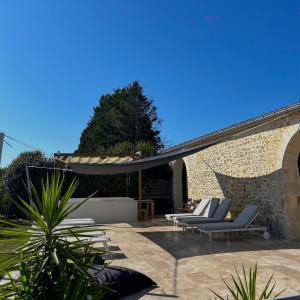 a patio with two lounge chairs and an umbrella at Château Bernon Gite 15 Personnes - piscine et SPA in Queyrac