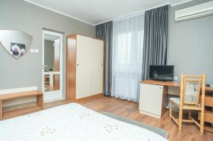 a bedroom with a bed and a desk and a television at Family Hotel Accent in Razgrad