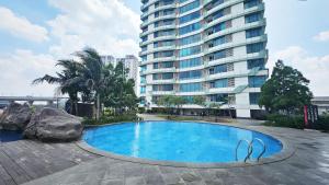 a swimming pool in front of a tall building at Grand Kamala Lagoon by Whitebox in Bekasi