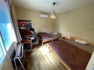 a man sitting at a desk in a room with a bed at This is Okinawa Nature Stay Yanbaru Forest in Motobu +37 photos