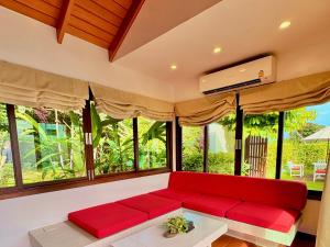 a red couch in a living room with windows at MAKALA Pool Villa in Choeng Mon Beach