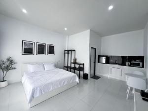 a white bedroom with a bed and a kitchen at SomeNights in Thong Sala +19 photos