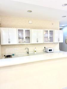 a kitchen with white cabinets and a microwave at شاليهات حياة روز in Taif
