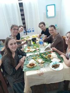 a group of people sitting around a table eating food at First Alleppey homestay in Alleppey