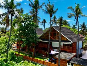 a house on a hill with palm trees at Four Elements Eco Dive Resort in Gili Islands