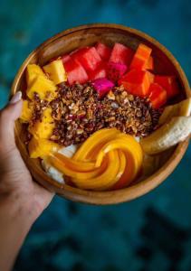 a person holding a bowl of food with fruit at Villa Cecilia Luxury with Sea view Pool - ANIMA Eco Lodge in Selong Belanak