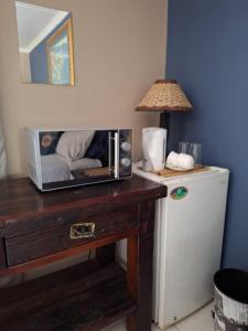 a microwave on a wooden table next to a refrigerator at The Pebble in Howick
