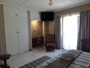 a bedroom with a bed and a chair and a window at The Pebble in Howick