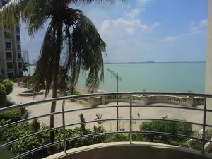 a balcony with a view of a beach and a palm tree at 1BR Seaview Condo with Balcony at Riviera Bay Resort, Melaka in Malacca +3 photos