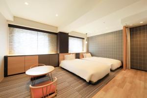 a hotel room with two beds and a table at Richmond Hotel Matsumoto in Matsumoto