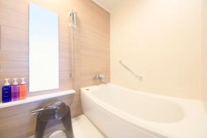 a bathroom with a white tub and a sink at Richmond Hotel Matsumoto in Matsumoto