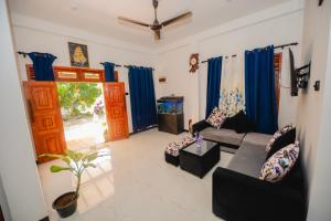a living room with a couch and blue curtains at Enu Homestay in Dickwella