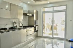 a kitchen with white cabinets and a large window at Aqua Azuri apartment in Mombasa