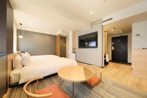 a bedroom with a bed and a table and a tv at Richmond Hotel Matsumoto in Matsumoto