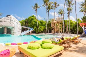 a woman laying on a raft in a pool at a resort at Soneva Jani in Dhigurah +74 photos