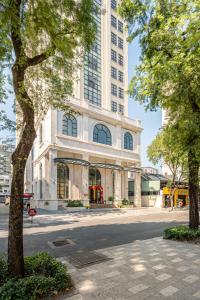 a large white building with a tree in front of it at Tao Dan Hotel in Ho Chi Minh City