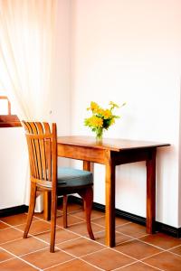 a wooden table with a chair and a vase of flowers at Samaya Waters Bentota in Haburugala
