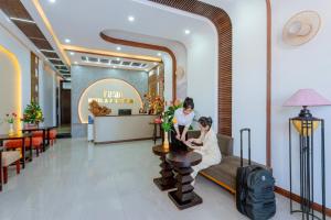 two women sitting at a table in a hotel lobby at Fusia Hotel & Apartment in Danang