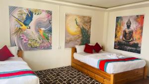 two beds in a room with paintings on the walls at Hotel Indrawoti and Resort in Dhulikhel