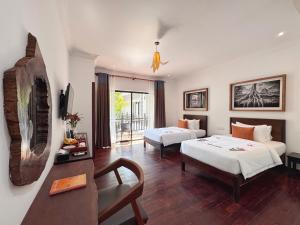 a hotel room with two beds and a couch at Emerald Angkor Siem Reap in Siem Reap