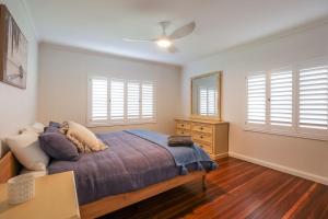 a bedroom with a bed and a dresser and windows at Bungalow Blue - 8 Illawong Lane in Evans Head
