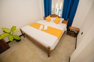 a bedroom with a bed with yellow and white sheets at Enu Homestay in Dickwella