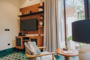 ein Wohnzimmer mit Fernseher, Sessel und Tisch in der Unterkunft CIGNO Mejorada Hotel Boutique in Mérida