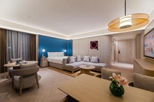 a hotel room with a couch and a bed at Orange Crystal Hotel Yantai Binhai Square in Yantai