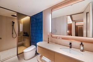 a bathroom with a sink and a toilet and a mirror at Orange Crystal Hotel Yantai Binhai Square in Yantai +27 photos
