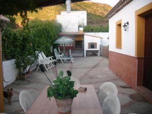 un patio con sillas blancas y una mesa con una planta en Casa Villazo I, en Almáchar