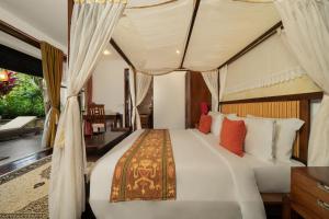 a bedroom with a large bed with a canopy at Villa Ambiente by Nakula in Jimbaran +12 photos