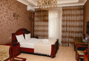 a bedroom with a bed and a desk and a chandelier at Royal Historical Boutique Hotel in Baku