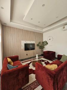a living room with two red couches and a tv at TiDise Villas & Chalets إستراحة وشاليه تايدايس in Bimmah