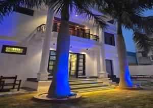 a white house with palm trees in front of it at HOTEL AYUSHMAN in Varanasi