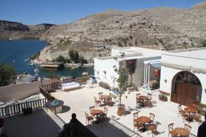 a patio with tables and chairs and a body of water at Kasr-ı Canan in Halfeti
