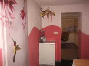 eine Küche mit einer roten Wand mit Blumen an der Wand in der Unterkunft Schusters Lindenhof in Bautzen
