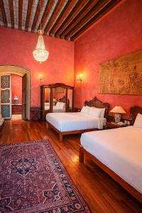 two beds in a room with red walls at La Casa de la Marquesa in Querétaro