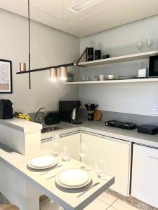 a kitchen with plates and wine glasses on a counter at St Oeste Superking Ar, Cozinha, Office, Vaga in Goiânia