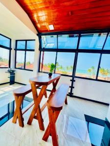 a table and two stools in a room with windows at Rehan Sunset Villa in Negombo
