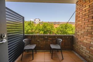 two chairs on a balcony with a brick wall at Belmore Hotel Maitland in Maitland