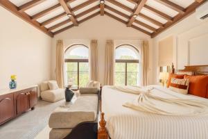 a bedroom with a bed and a chair and windows at ELIVAAS Signature Casa Verdea 4-BHK Villa With Private Pool & Lift Near Popular Restaurants in Siolim