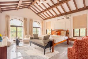 a bedroom with a bed and a chair and windows at ELIVAAS Signature Casa Verdea 4-BHK Villa With Private Pool & Lift Near Popular Restaurants in Siolim