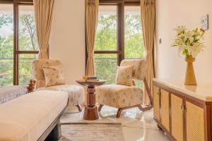 two chairs and a bed in a room with windows at ELIVAAS Signature Casa Verdea 4-BHK Villa With Private Pool & Lift Near Popular Restaurants in Siolim +54 photos
