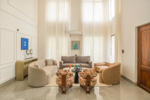 a living room with two chairs and a table at ELIVAAS Signature Casa Verdea 4-BHK Villa With Private Pool & Lift Near Popular Restaurants in Siolim