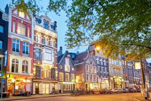 une rangée de bâtiments dans une rue urbaine la nuit dans l'établissement Hotel The Bird, à Amsterdam