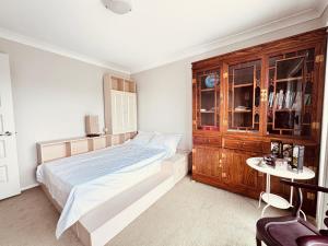a bedroom with a large bed and a wooden cabinet at A Zen Tea Sanctuary in Australia in Schofields